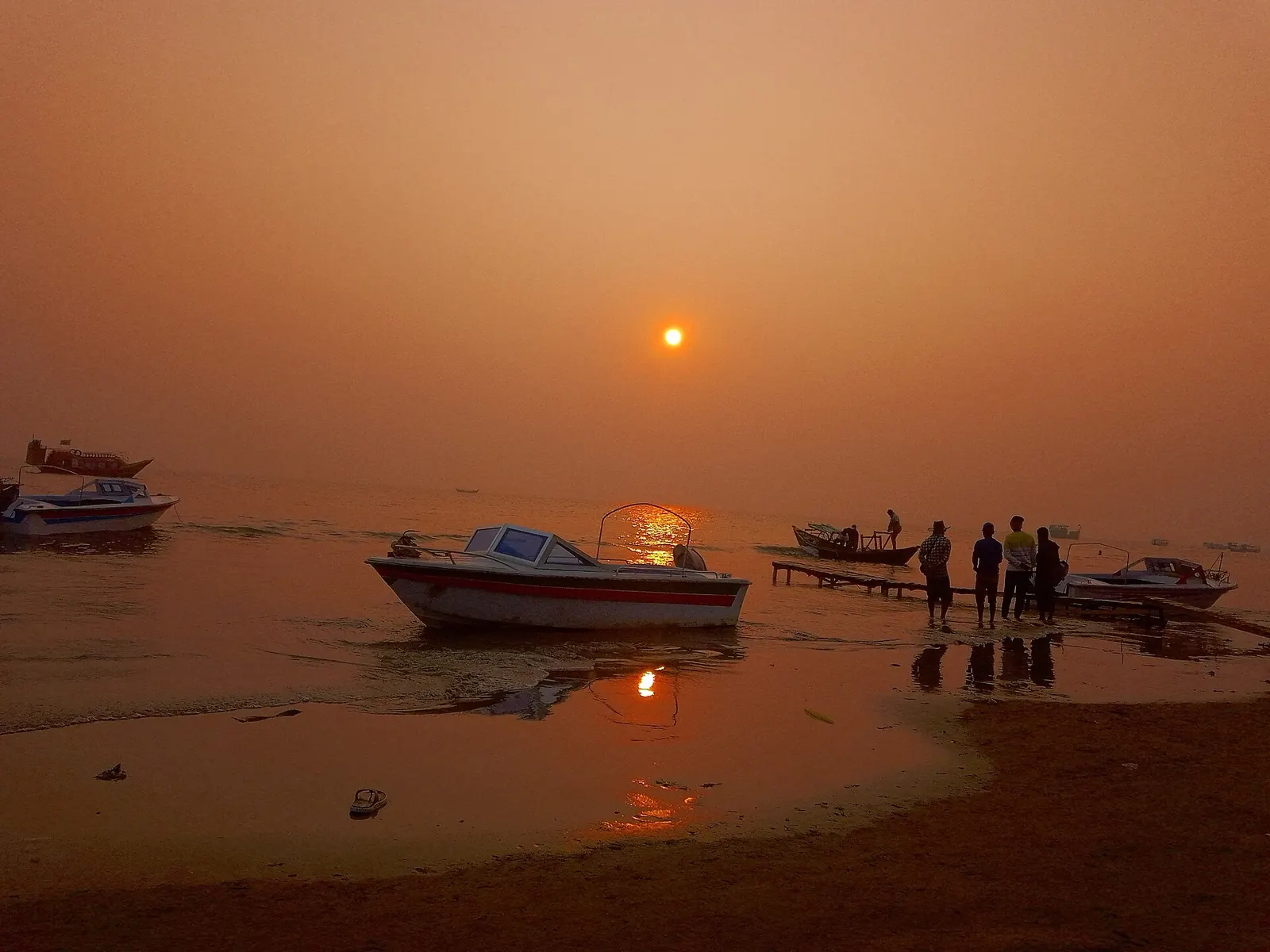 Boats pulled up on the shore at Kuakata as the sun sets over the water