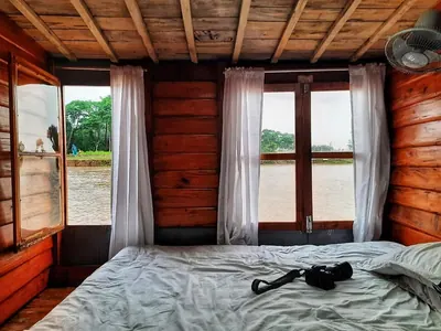 A bed in a wood-panelled cabin looking out over the haor